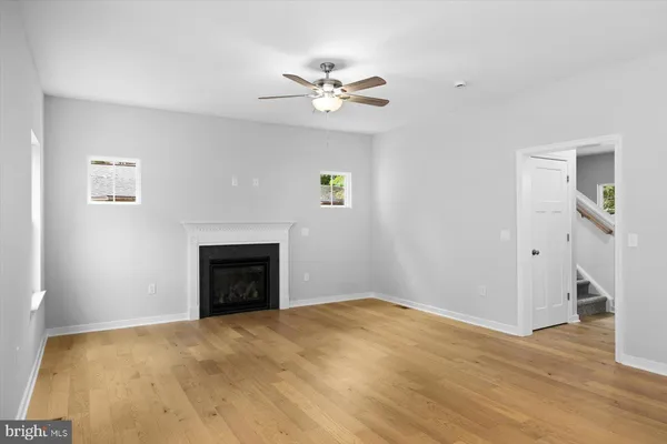 a view of an empty room with wooden floor and a fireplace