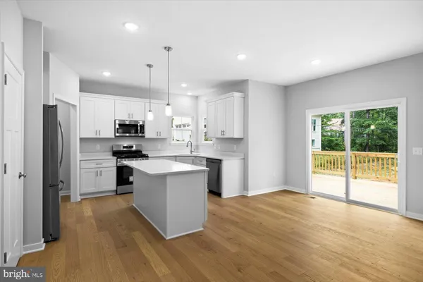 a kitchen with stainless steel appliances granite countertop a refrigerator a sink dishwasher a stove and white countertops with wooden floor