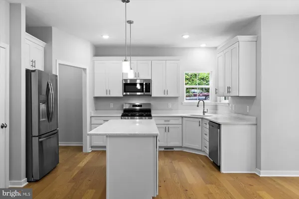 a kitchen with a sink a center island stainless steel appliances and cabinets