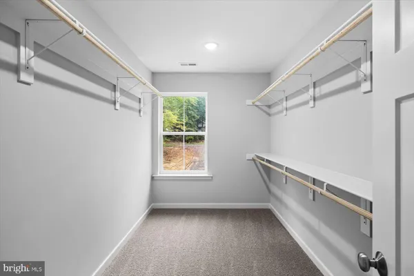 an empty room with a chandelier fan and windows