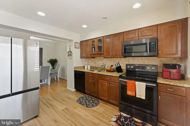 a kitchen with stainless steel appliances granite countertop a stove a sink dishwasher a microwave oven and a refrigerator with wooden cabinets