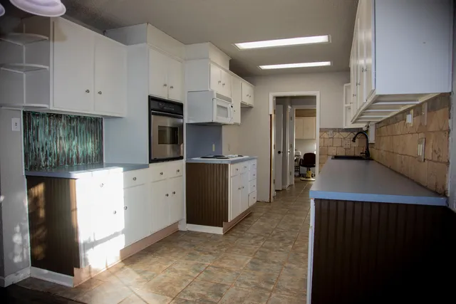 a kitchen with stainless steel appliances kitchen island granite countertop a refrigerator oven a stove with white cabinets