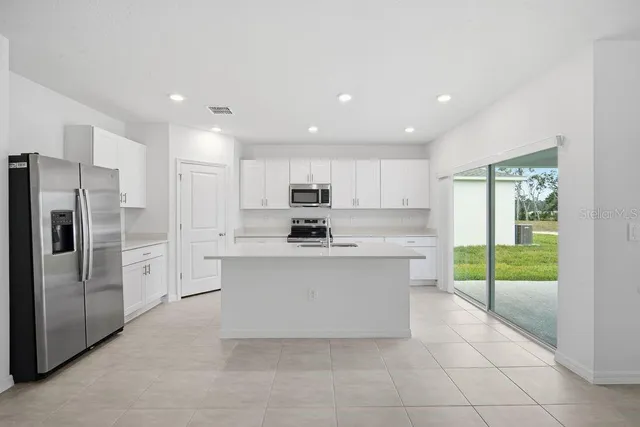 a large white kitchen with a refrigerator a sink and a stove