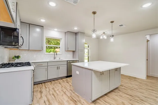 a kitchen with a stove a sink a microwave a center island and cabinets