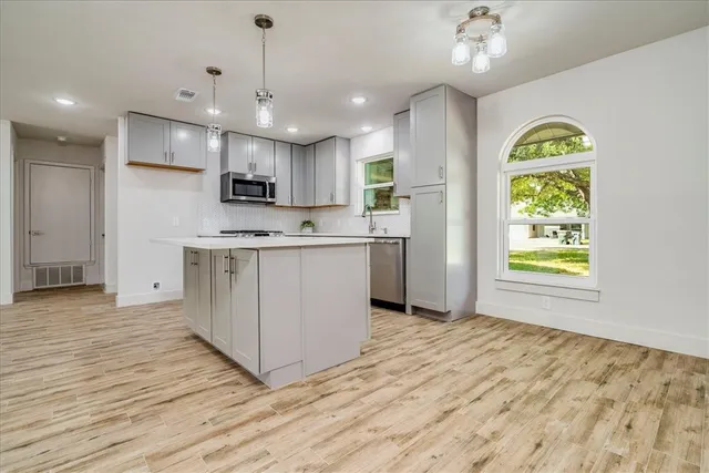 a view of kitchen with stainless steel appliances granite countertop a stove a sink dishwasher and a refrigerator with wooden floor