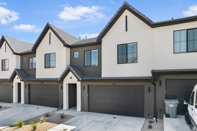 Contemporary townhome exterior with a multi-tone facade, prominent gables, dark-framed windows, and a two-car garage
