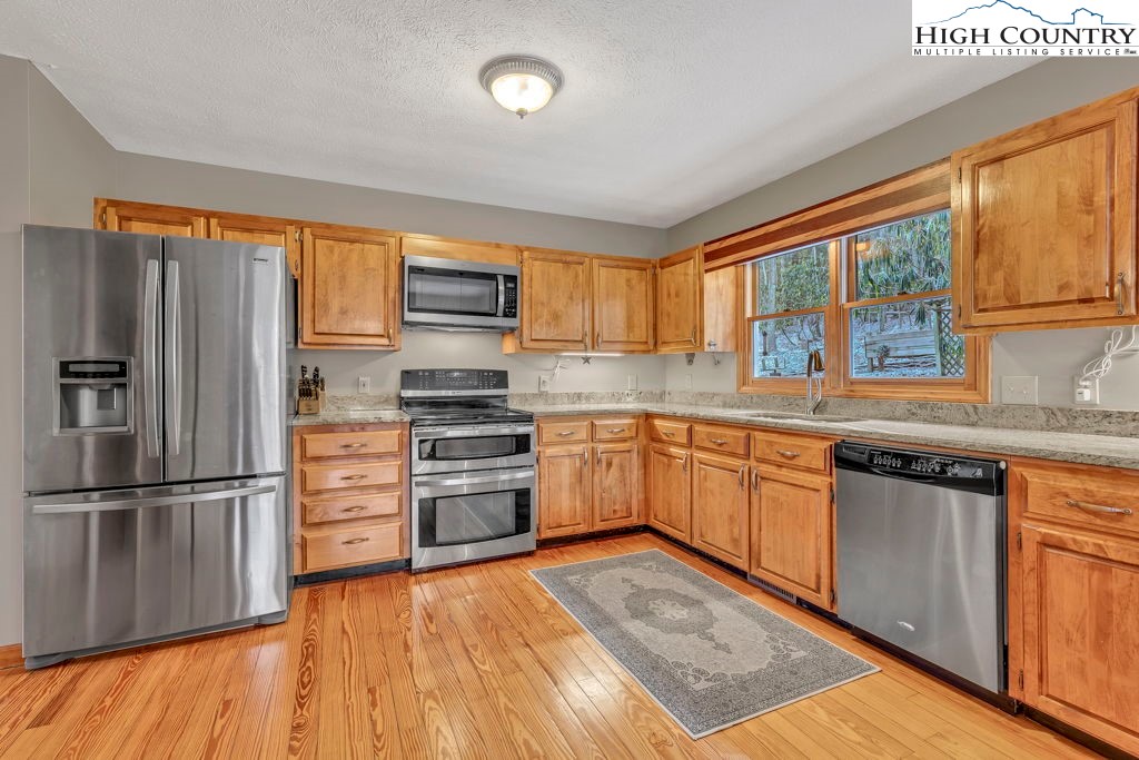 472 Virgil's Lane Boone, NC 28607 - Photo 14 of 44 a kitchen with stainless steel appliances granite countertop a refrigerator a sink dishwasher a stove and white cabinets with wooden floor