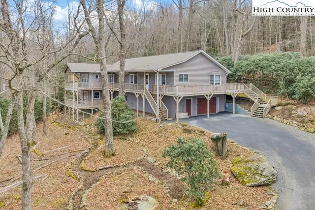 a view of a wooden house with a big yard and potted plants