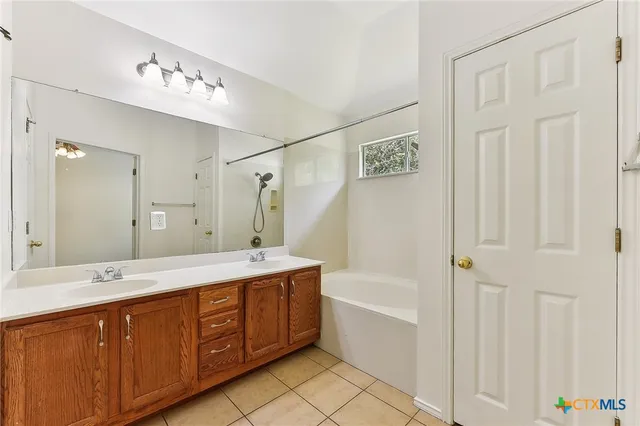 a spacious bathroom with a double vanity sink a mirror and a bathtub