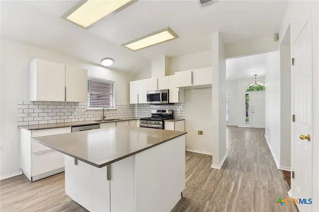 a kitchen with kitchen island a counter top space a sink a stove and refrigerator