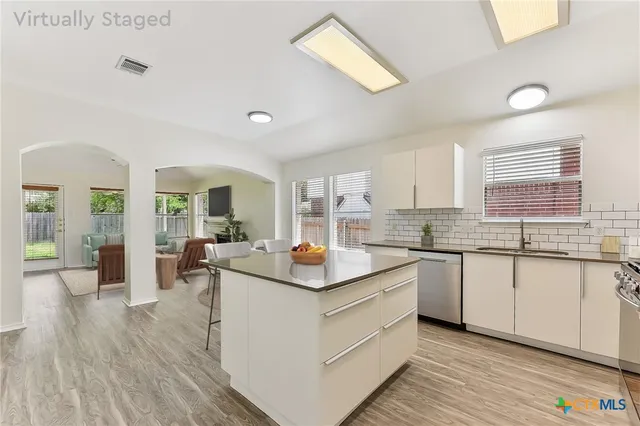 a kitchen with white cabinets and sink