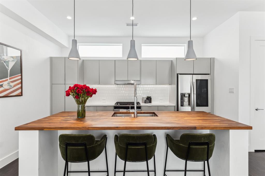 Kitchen with butcher block island and stone counters, gray cabinetry, dark wood-type flooring, decorative backsplash, and recessed lighting