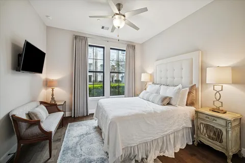 a bedroom with a bed a couch and a flat tv screen on dresser