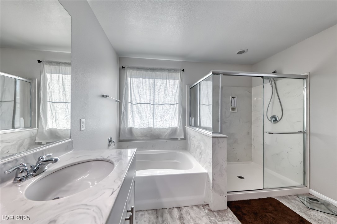 723 Gorringe Ridge Court Henderson, NV 89002 - Photo 26 of 48 Full bathroom with vanity, a garden tub, light wood-style flooring, a marble finish shower, and a textured ceiling