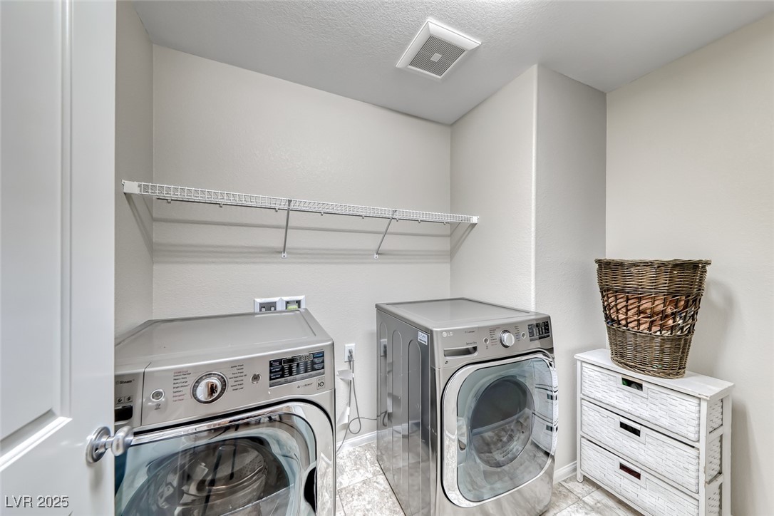 723 Gorringe Ridge Court Henderson, NV 89002 - Photo 32 of 48 Laundry room featuring washing machine and dryer, light tile patterned floors, and a textured ceiling