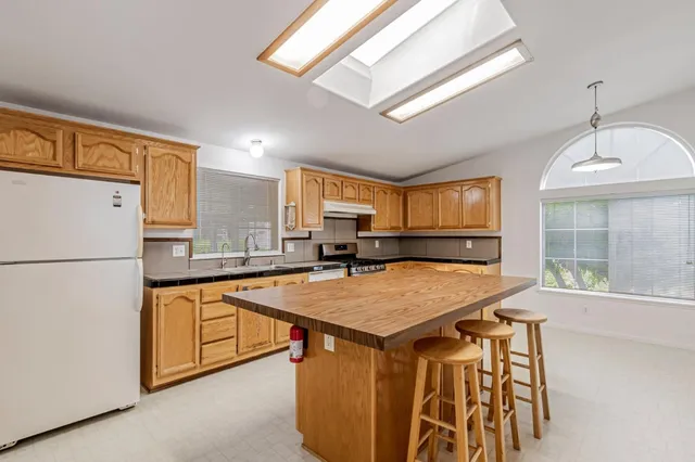 a kitchen with stainless steel appliances granite countertop a sink a refrigerator and a stove