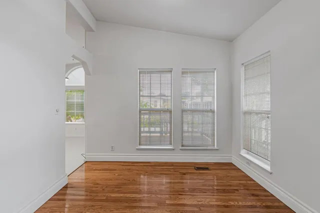 a view of an empty room with wooden floor and a window