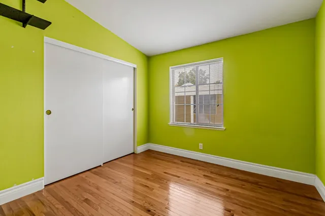 a view of an empty room with wooden floor and a window