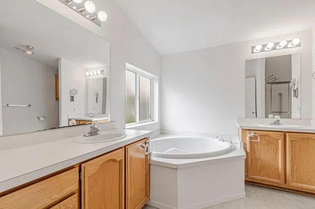 a bathroom with a sink double vanity granite tub and a mirror