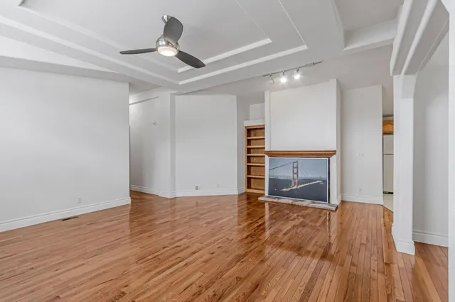 a view of an empty room with a window and wooden floor