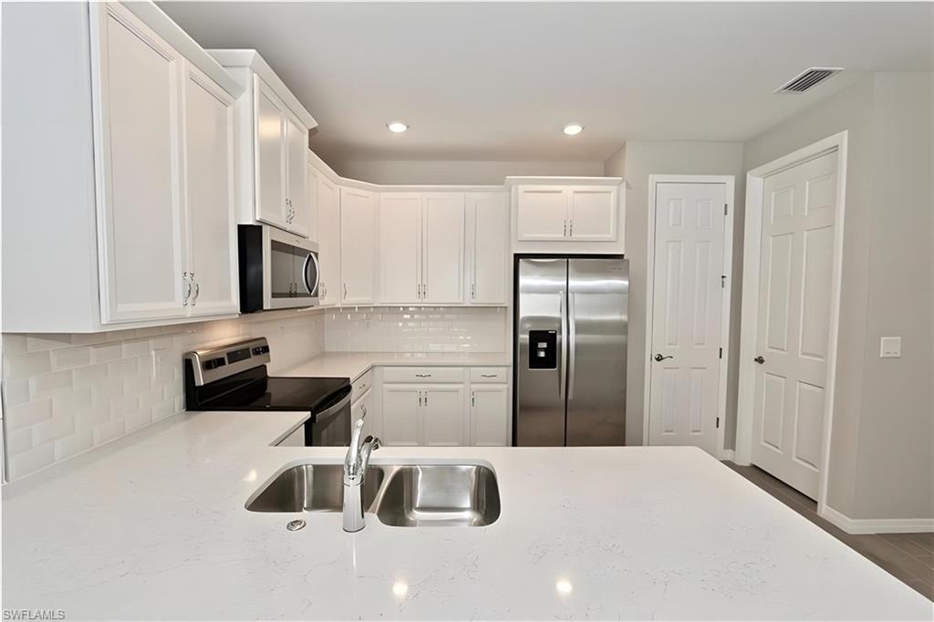 1264 Enbrook Loop Naples, FL 34114 - Photo 14 of 27 a kitchen with granite countertop a refrigerator sink and white cabinets