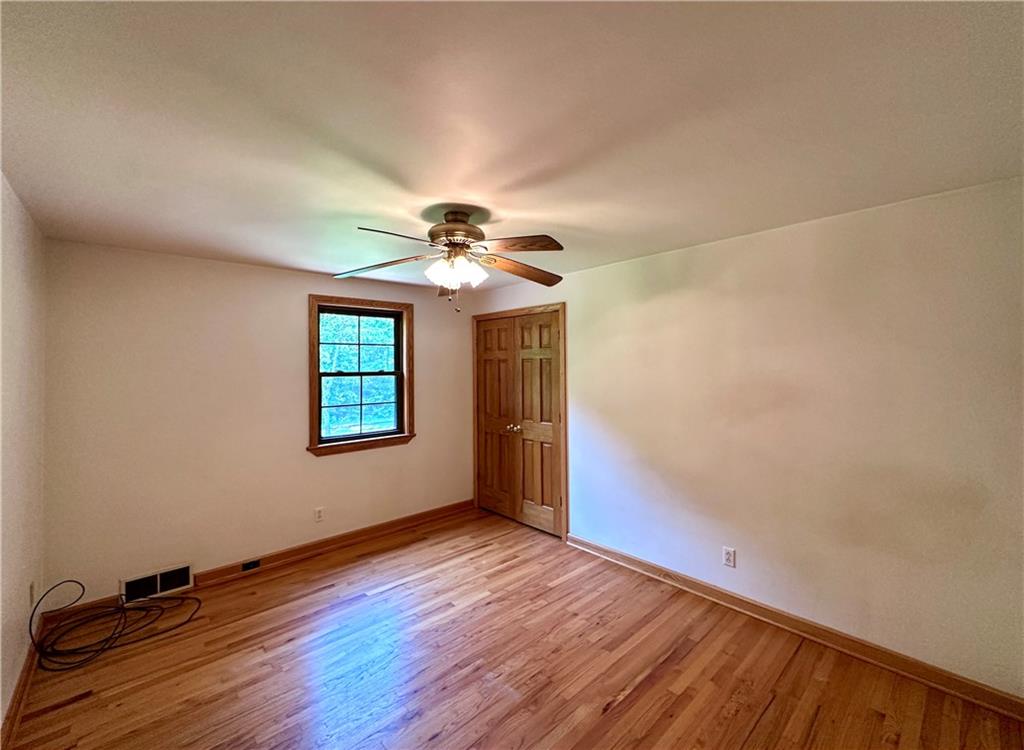 752 Covered Bridge Road Volant, PA 16156 - Photo 23 of 48 an empty room with wooden floor chandelier fan and windows