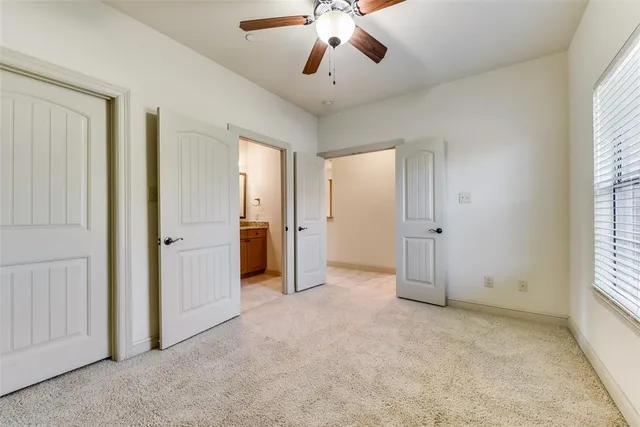 an empty room with chandelier fan and windows