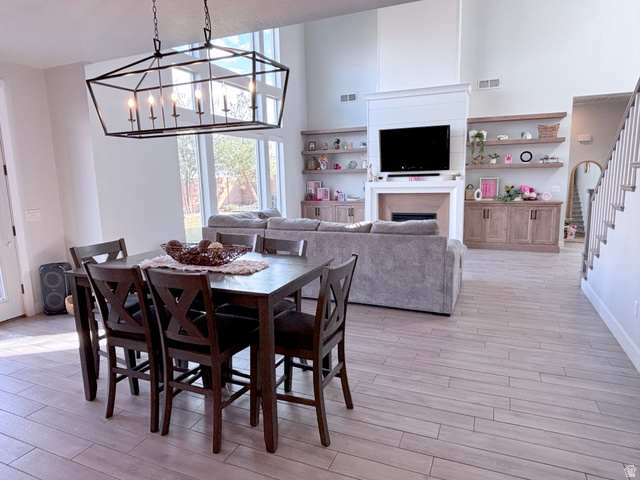 429 East Treasure Road Washington, UT 84780 - Photo 13 of 36 Dining area featuring a high ceiling, light wood-style floors, suspended lighting, and a fireplace