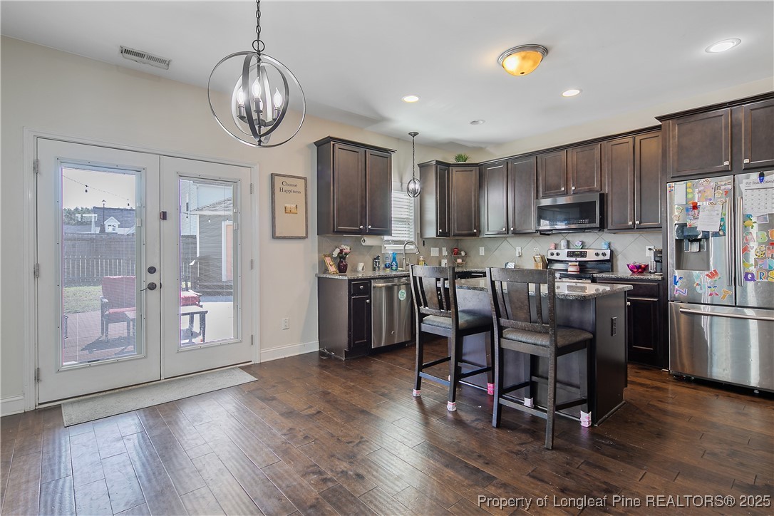 688 Stonebriar Avenue Raeford, NC 28376 - Photo 11 of 50 a kitchen with stainless steel appliances granite countertop a refrigerator a stove top oven a sink dishwasher a dining table and chairs with wooden floor