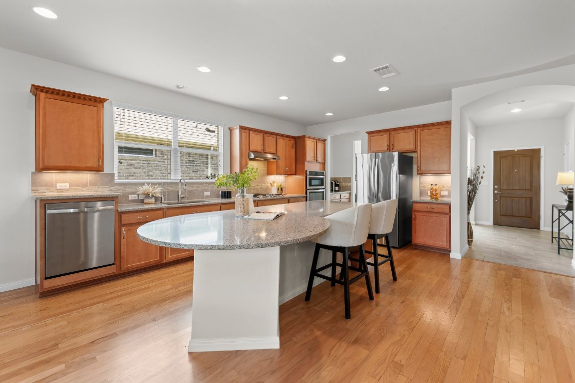 608 Kite Ridge Street Georgetown, TX 78633 - Photo 17 of 39 a kitchen with stainless steel appliances granite countertop wooden floor a dining table and chairs