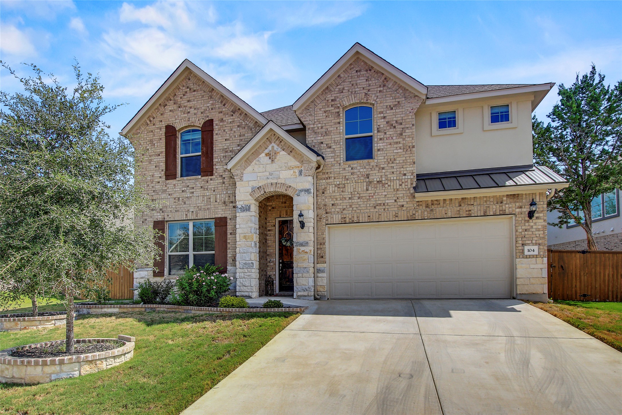 104 Millbend Road Georgetown, TX 78633 - Photo 1 of 40 A striking facade with varied brick and stone elements, featuring a welcoming arched entry and an attached garage.