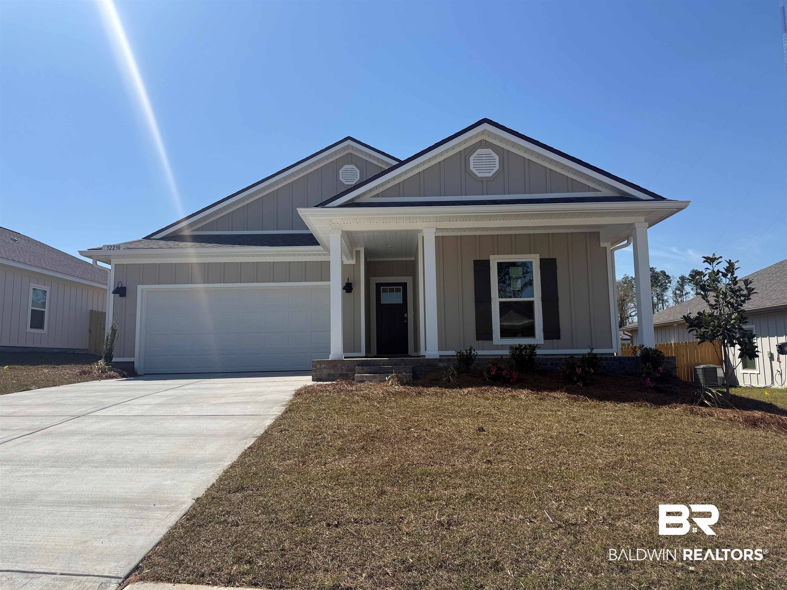 32250 Lyon Road Daphne, AL 36527 - Photo 1 of 30 View of front of house featuring board and batten siding, an attached garage, a porch, concrete driveway, and a front lawn