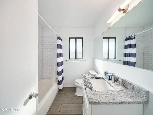 a bathroom with a granite countertop sink a toilet and bathtub
