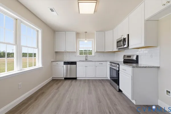 a kitchen with cabinets wooden floor and a window
