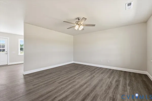 an empty room with wooden floor and a ceiling fan