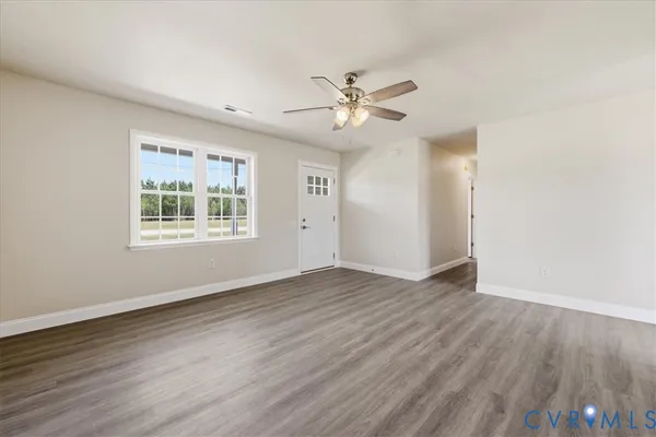 a view of an empty room with wooden floor and a window