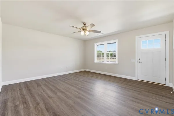 an empty room with wooden floor ceiling fan and windows