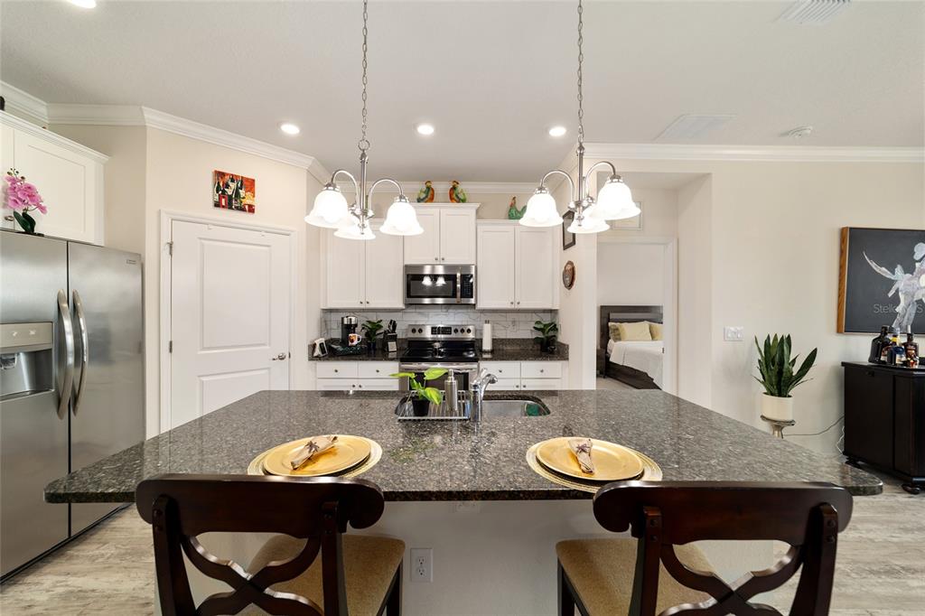 9238 Southwest 60th Terrace Road Ocala, FL 34476 - Photo 19 of 50 a kitchen with stainless steel appliances kitchen island granite countertop a dining table and chairs