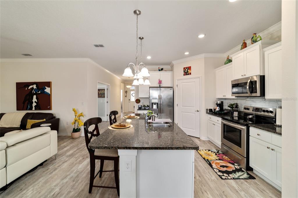 9238 Southwest 60th Terrace Road Ocala, FL 34476 - Photo 22 of 50 a kitchen with stainless steel appliances granite countertop a sink dishwasher a microwave oven a refrigerator with white cabinets and wooden floor