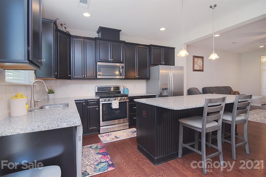 1411 Calum Way Fort Mill, SC 29708 - Photo 7 of 37 a kitchen with stainless steel appliances granite countertop a table chairs sink refrigerator and microwave
