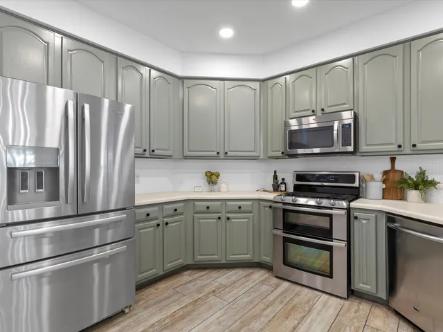 a kitchen with stainless steel appliances granite countertop a refrigerator and a stove top oven
