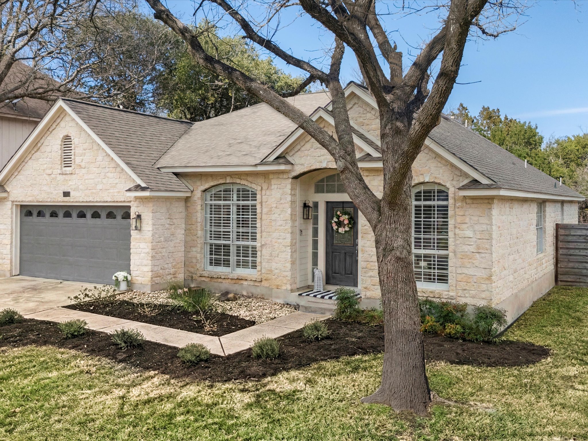 9322 Lightwood Loop Austin, TX 78748 - Photo 7 of 40 Mature landscaping, shade trees, stone masonry, and a two-car garage create a welcoming first impression.