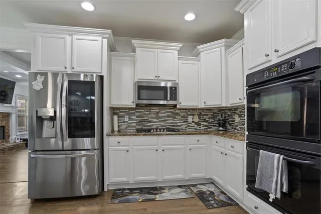 a kitchen with granite countertop white cabinets and stainless steel appliances