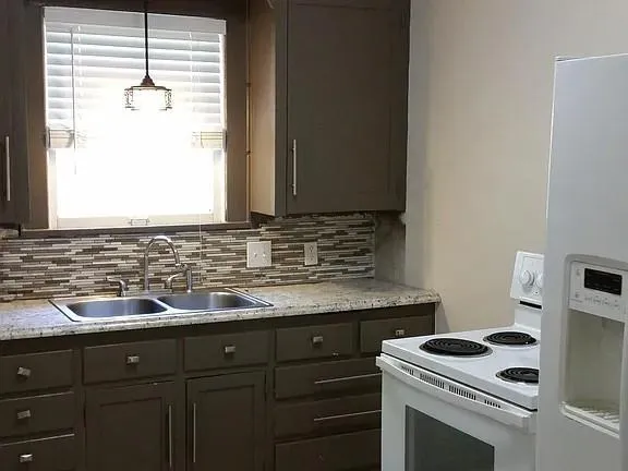a kitchen with granite countertop cabinets sink appliances and a window
