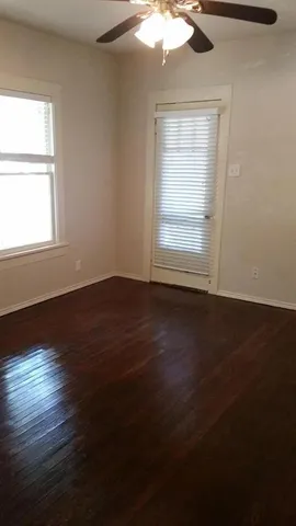 a view of an empty room with wooden floor and a window