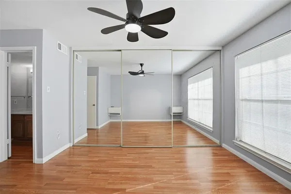 a view of empty room with wooden floor and fan