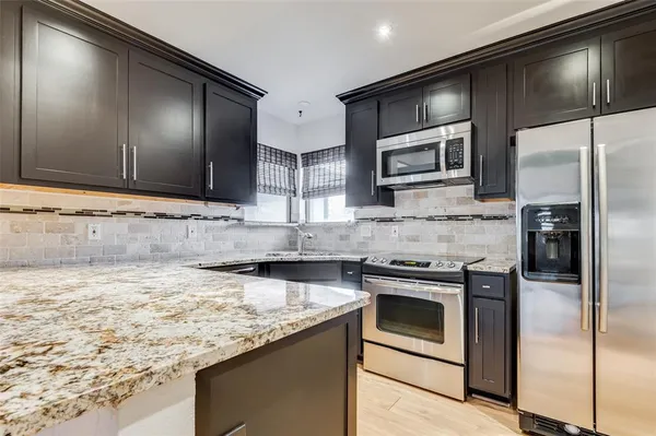 a kitchen with stainless steel appliances granite countertop a sink stove and refrigerator
