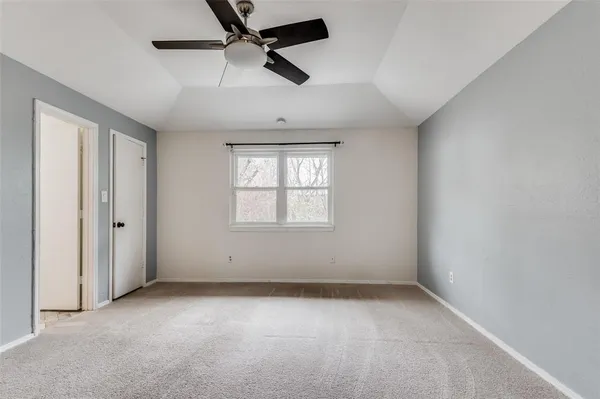 an empty room with a ceiling fan and window
