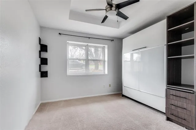 an empty room with windows and ceiling fan