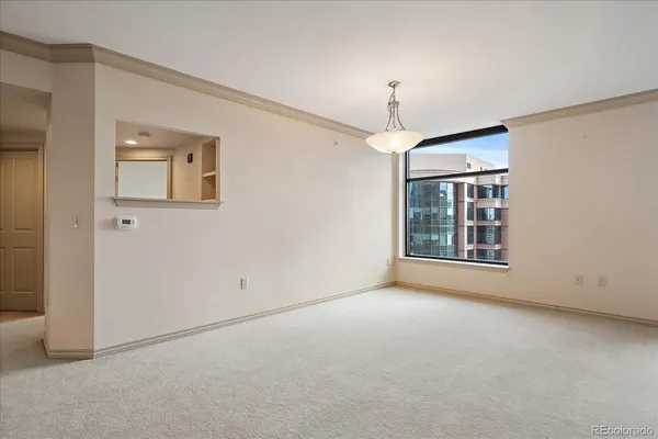 an empty room with chandelier fan and windows